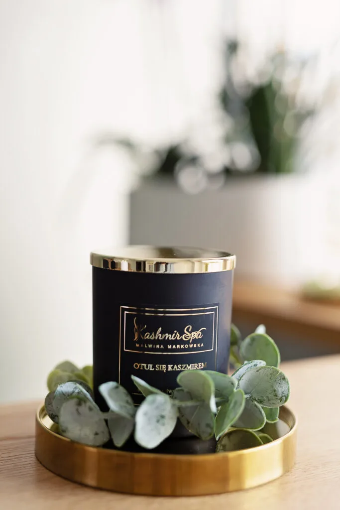 Galeria zdjęć przedstawiająca elegancką świecę zapachową od Kashmir SPA Malwina Markowska na złotej tacy.