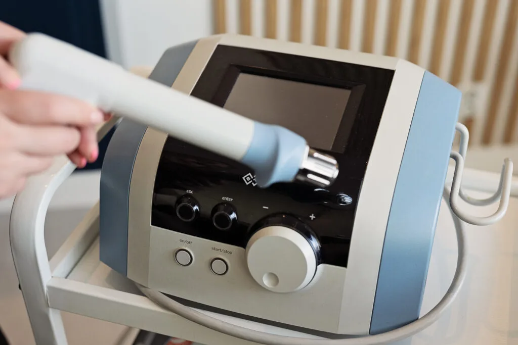 Aparat do terapii falą uderzeniową BTL używany w zabiegu odmładzającym, obsługiwany przez specjalistkę.