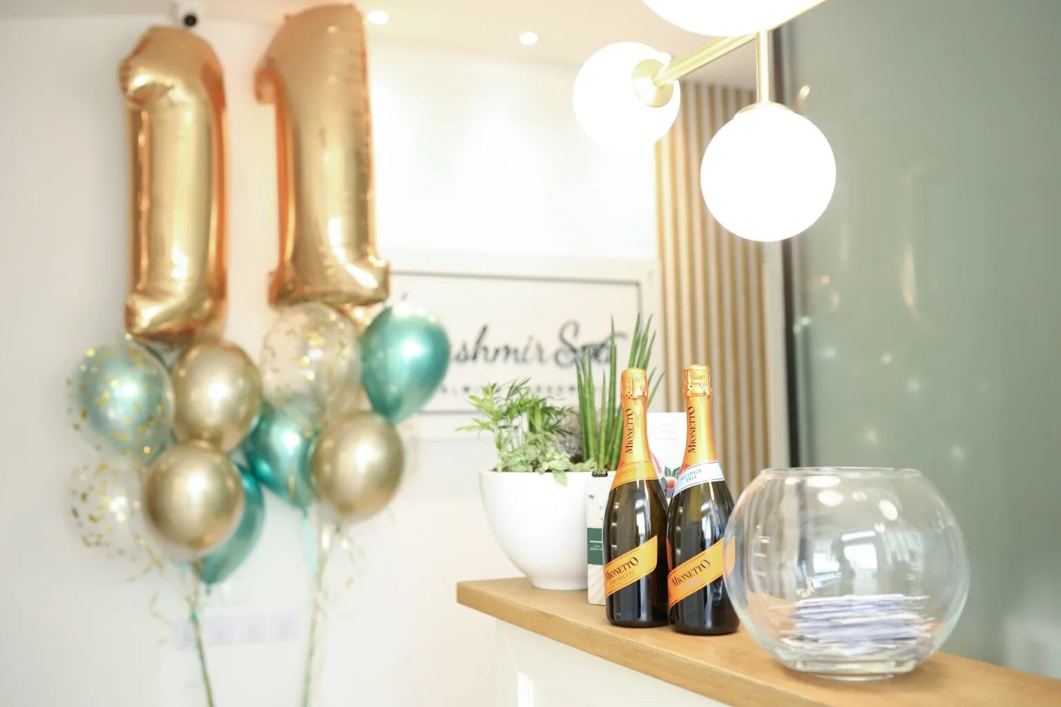 Stół z butelkami prosecco i kolorowymi balonami z cyframi "11", dekoracjami na 11 URODZINY Kashmir SPA.