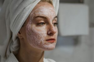 A woman applies a facial cream as part of a relaxing skincare routine indoors.