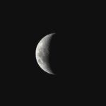 A detailed view of the crescent moon set against a dark night sky, showcasing lunar texture.