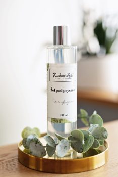 Galeria zdjęć przedstawiająca elegancki żel pod prysznic Kashmir SPA Malwina Markowska na złotej tacy, otoczony dekoracyjnymi zielonymi liśćmi.