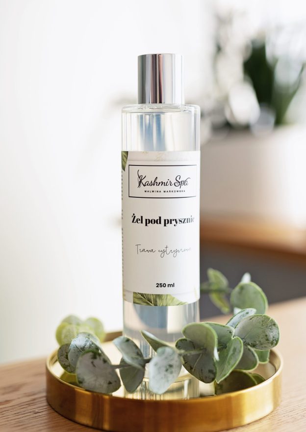 Galeria zdjęć przedstawiająca elegancki żel pod prysznic Kashmir SPA Malwina Markowska na złotej tacy, otoczony dekoracyjnymi zielonymi liśćmi.