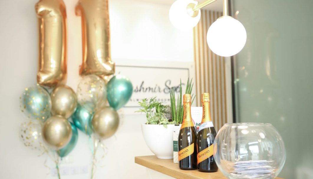 Stół z butelkami prosecco i kolorowymi balonami z cyframi "11", dekoracjami na 11 URODZINY Kashmir SPA.