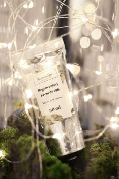 Opakowanie regenerującego kremu do rąk Kashmir SPA, otoczone dekoracyjnymi światłami i zielenią na 11 URODZINY Kashmir Spa.